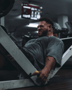 A determined man exercises on a leg press machine, showcasing strength and concentration.