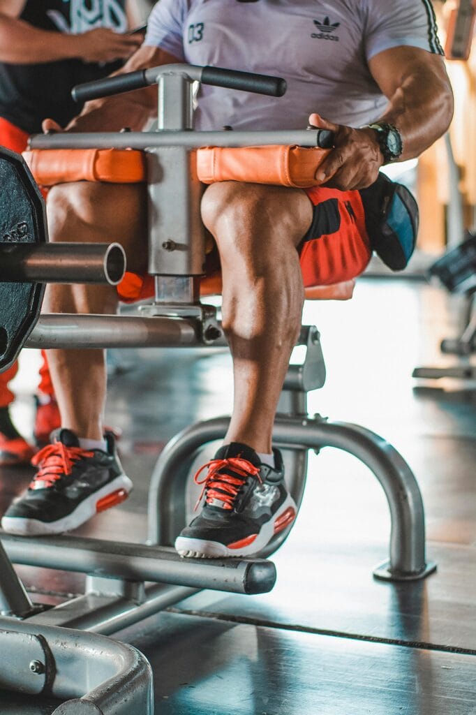 Adult man working out on a leg exercise machine in a modern indoor gym.