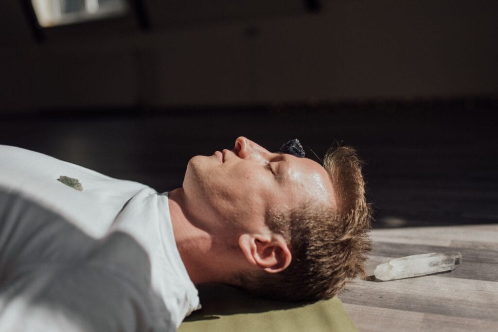 Man meditating indoors with crystals, focusing on relaxation and healing energy.