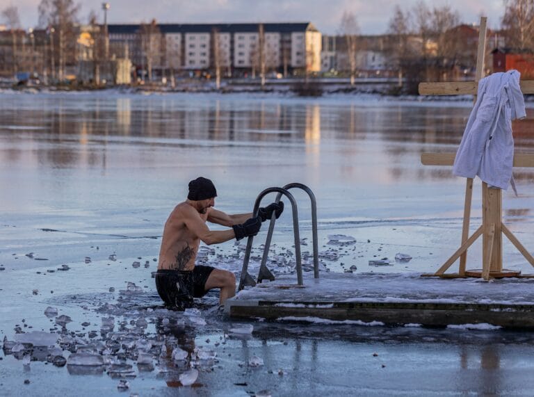 Shirtless man in freezing lake near Ludvika, Sweden, captured during a winter swim. Sublime ice scenery. | cold plunge