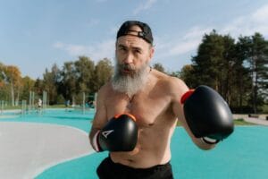 Elderly man practicing boxing outdoors, showcasing fitness and strength.