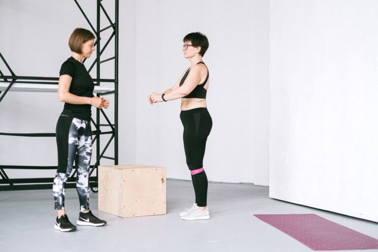 Two women exercising indoors, focusing on fitness and healthy lifestyle with guidance.