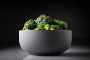 Close-up of fresh broccoli in a stylish black bowl against a dark background.