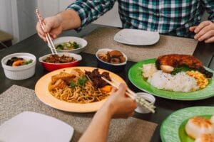 A delicious Asian meal featuring noodles, meats, and vegetables served with chopsticks on a dining table.