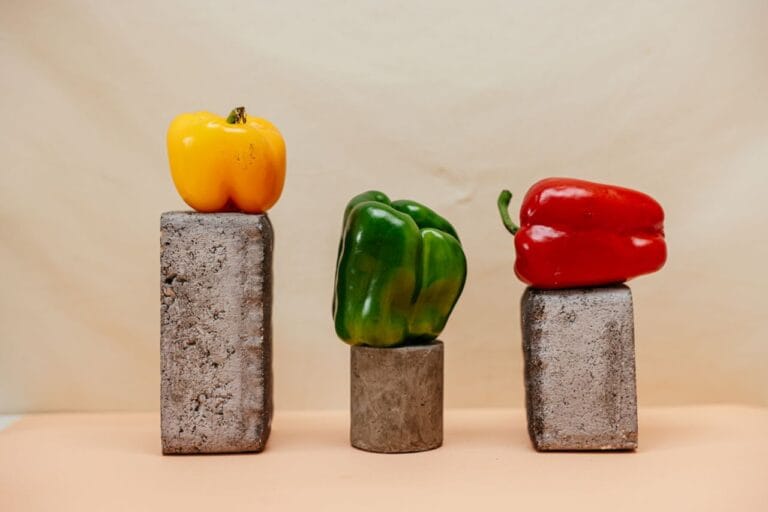 Three bell peppers arranged on concrete blocks in a studio setting, showcasing vibrant colors.