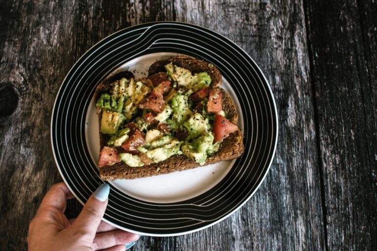 A slice of hearty avocado toast with tomatoes served on a stylish plate. Perfect for healthy vegan eating.