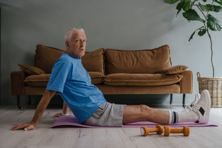 Senior man exercising indoors on a yoga mat with dumbbells. Health and fitness lifestyle.