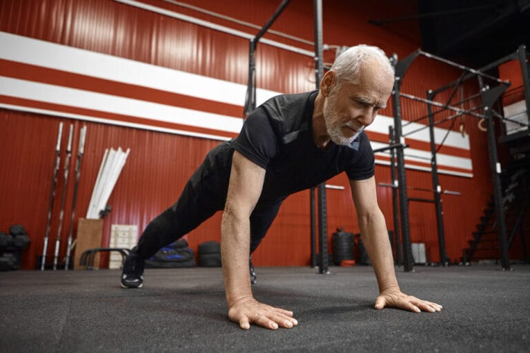 senior man doing pushups in the gym